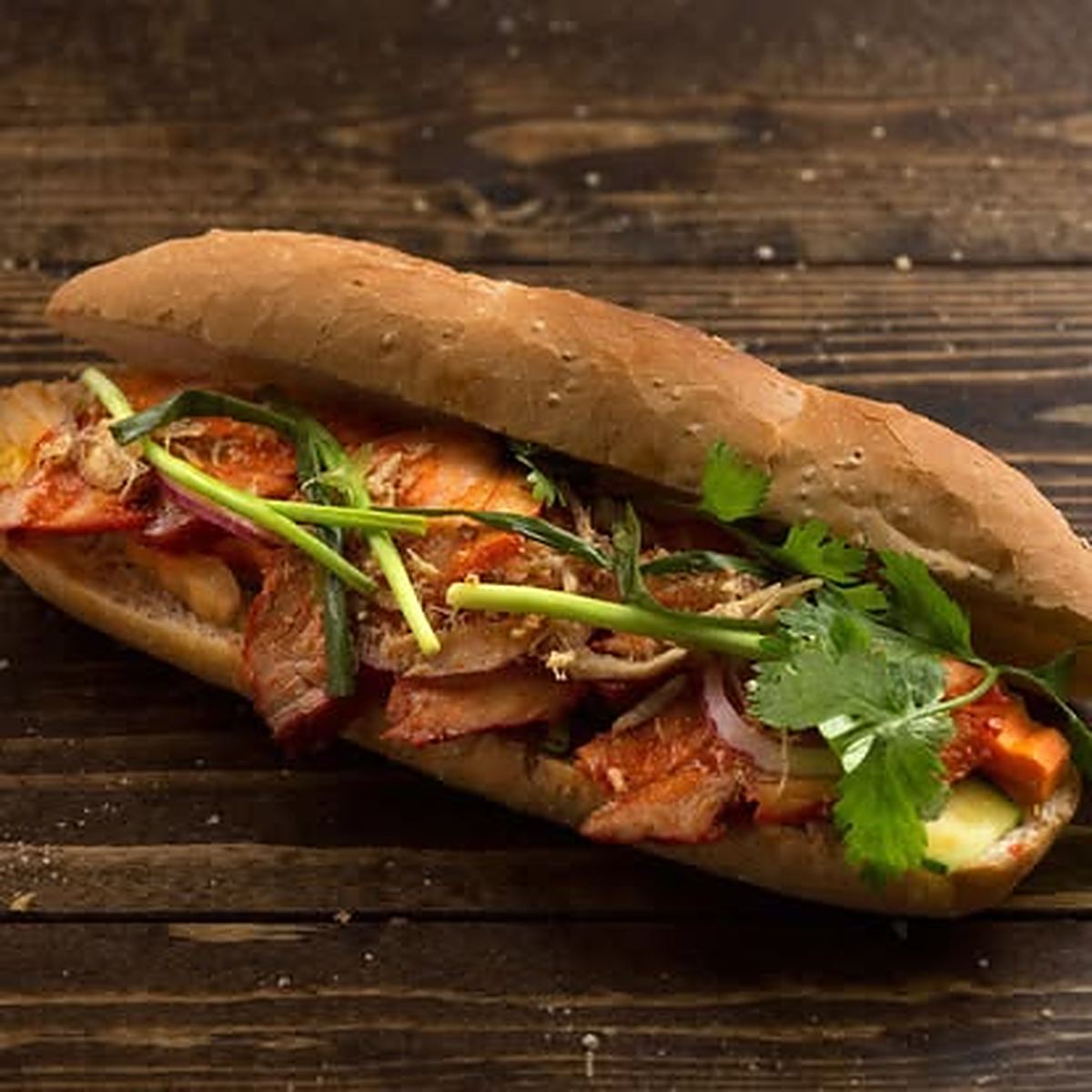 Banh mi sandwich filled with char siu pork and fresh herbs